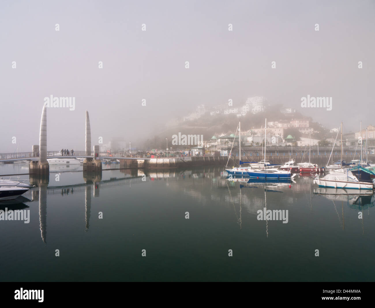 Vue sur le port de Torquay sur un matin, encore, avec sea mist enveloppant les bâtiments. Banque D'Images