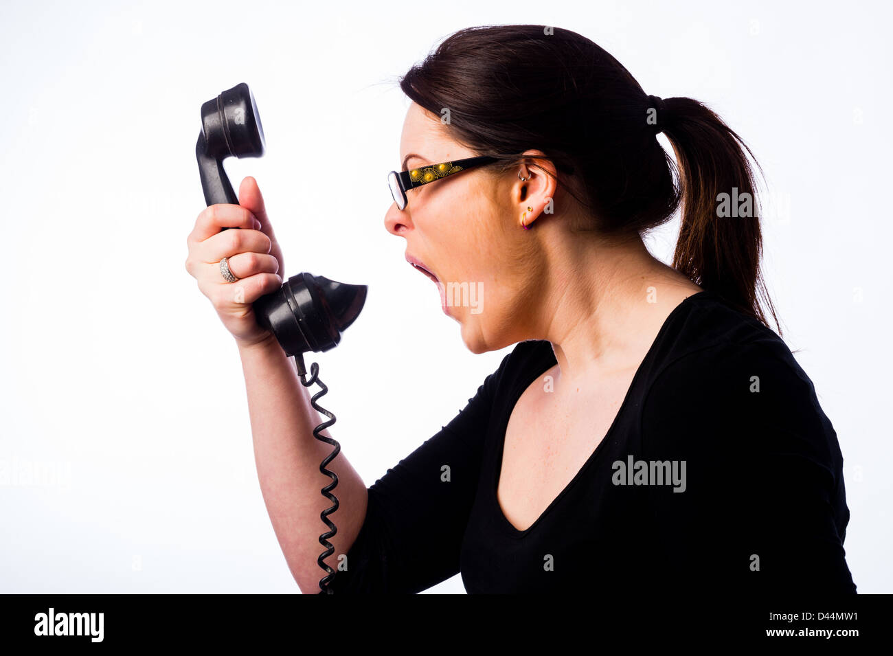 Une jeune femme, les cheveux bruns, criant dans un ancien téléphone, UK Centre d'appel de la ligne d'aide d'appel Banque D'Images
