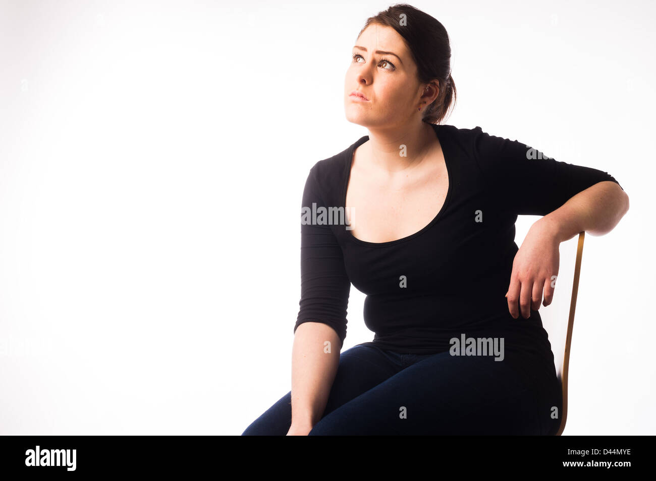 Une jeune femme, les cheveux bruns, assise seule, à la triste bas enfoncé lonely UK Banque D'Images