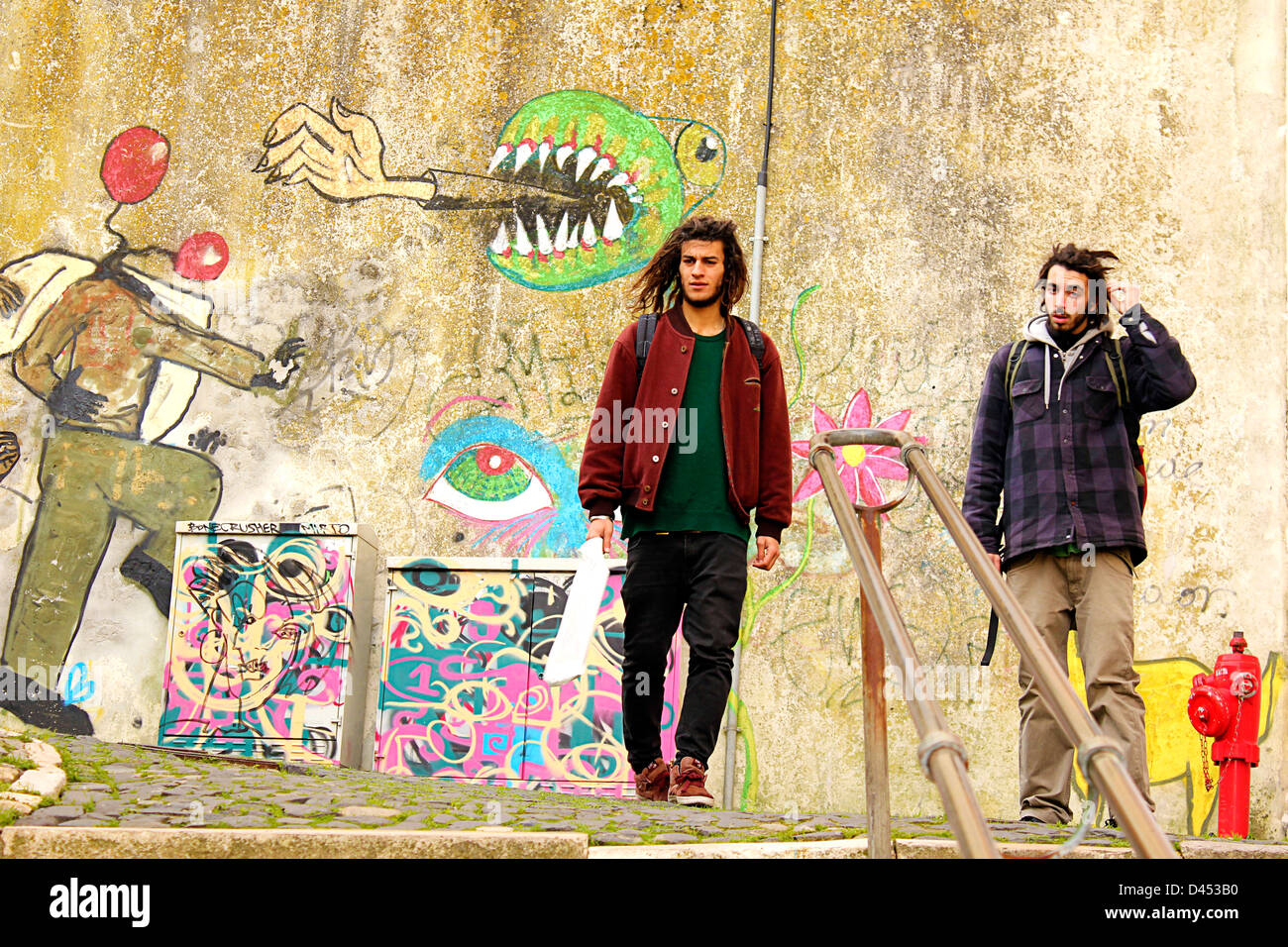 Deux jeunes hommes style hippie en face de l'écriture graffiti mur peint à Lisbonne, Portugal Banque D'Images