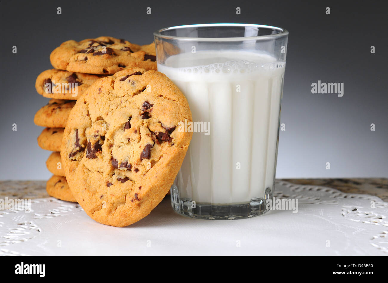 Pile de cookies aux pépites de chocolat à côté d'un verre de lait. Format horizontal sur un arrière-plan clair à foncé. Banque D'Images