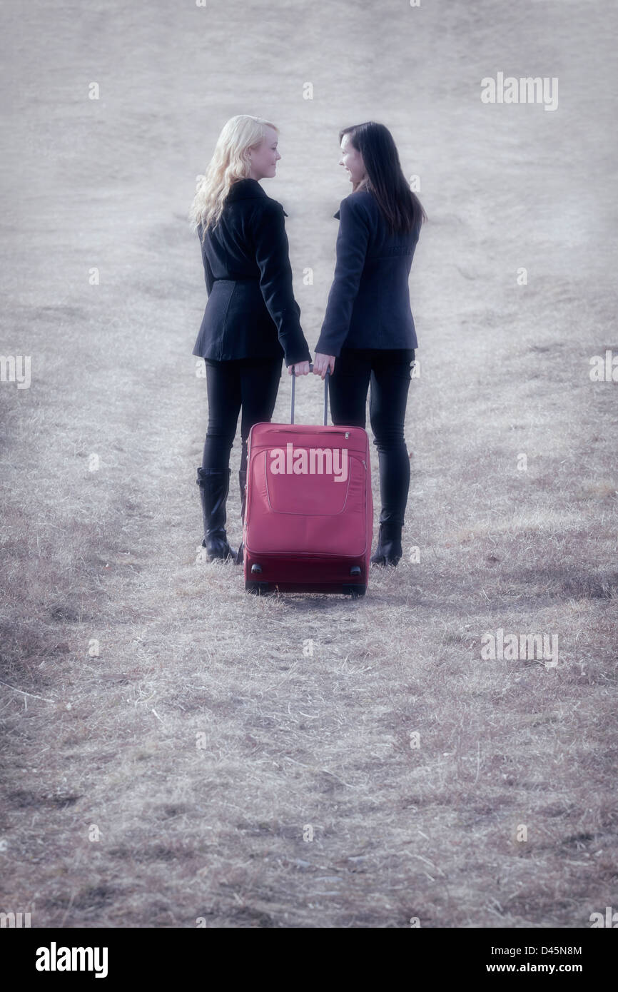 Deux copines avec une valise rouge, rire Banque D'Images