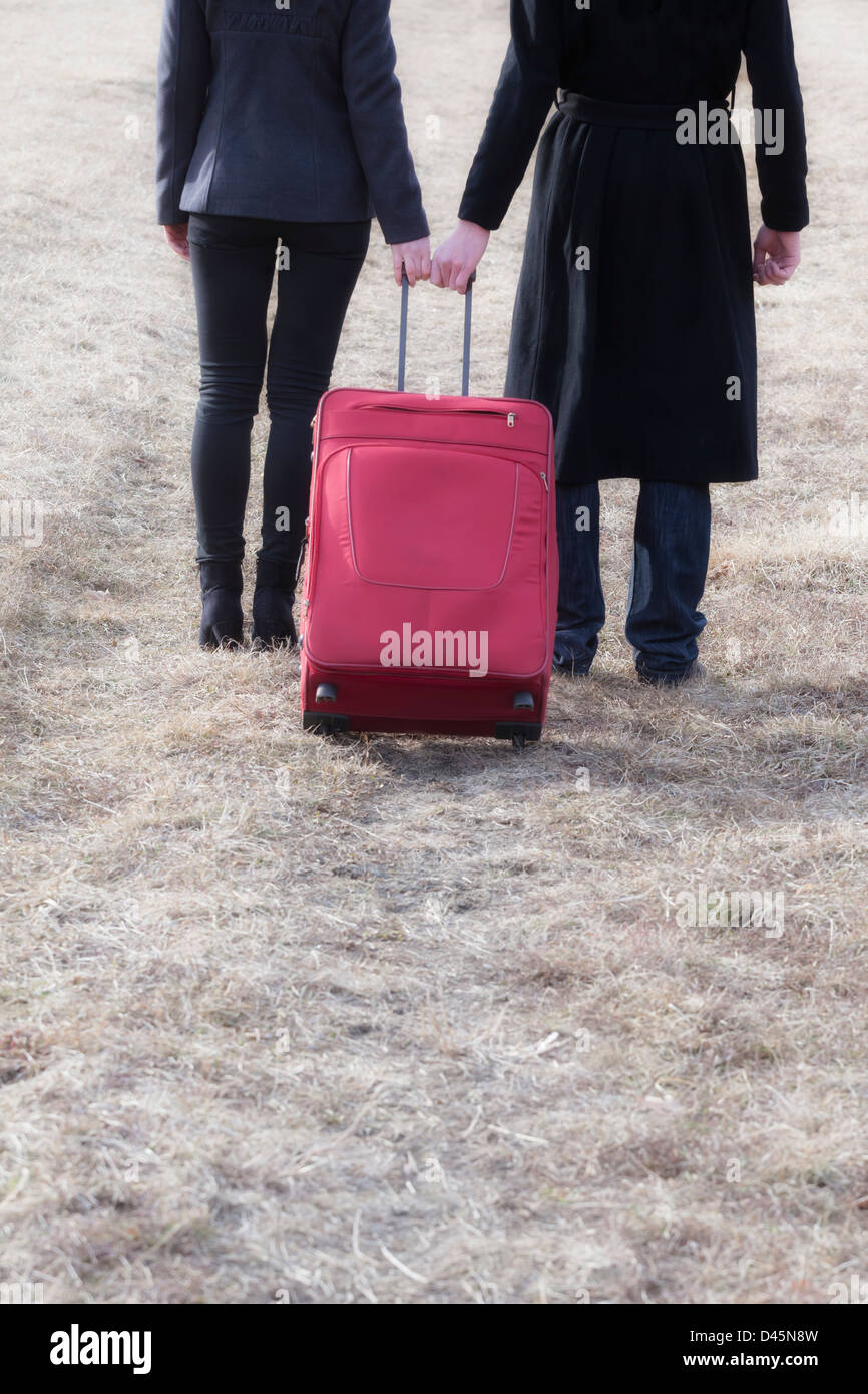 Détail tourné d'un couple qui tire une valise rouge Banque D'Images