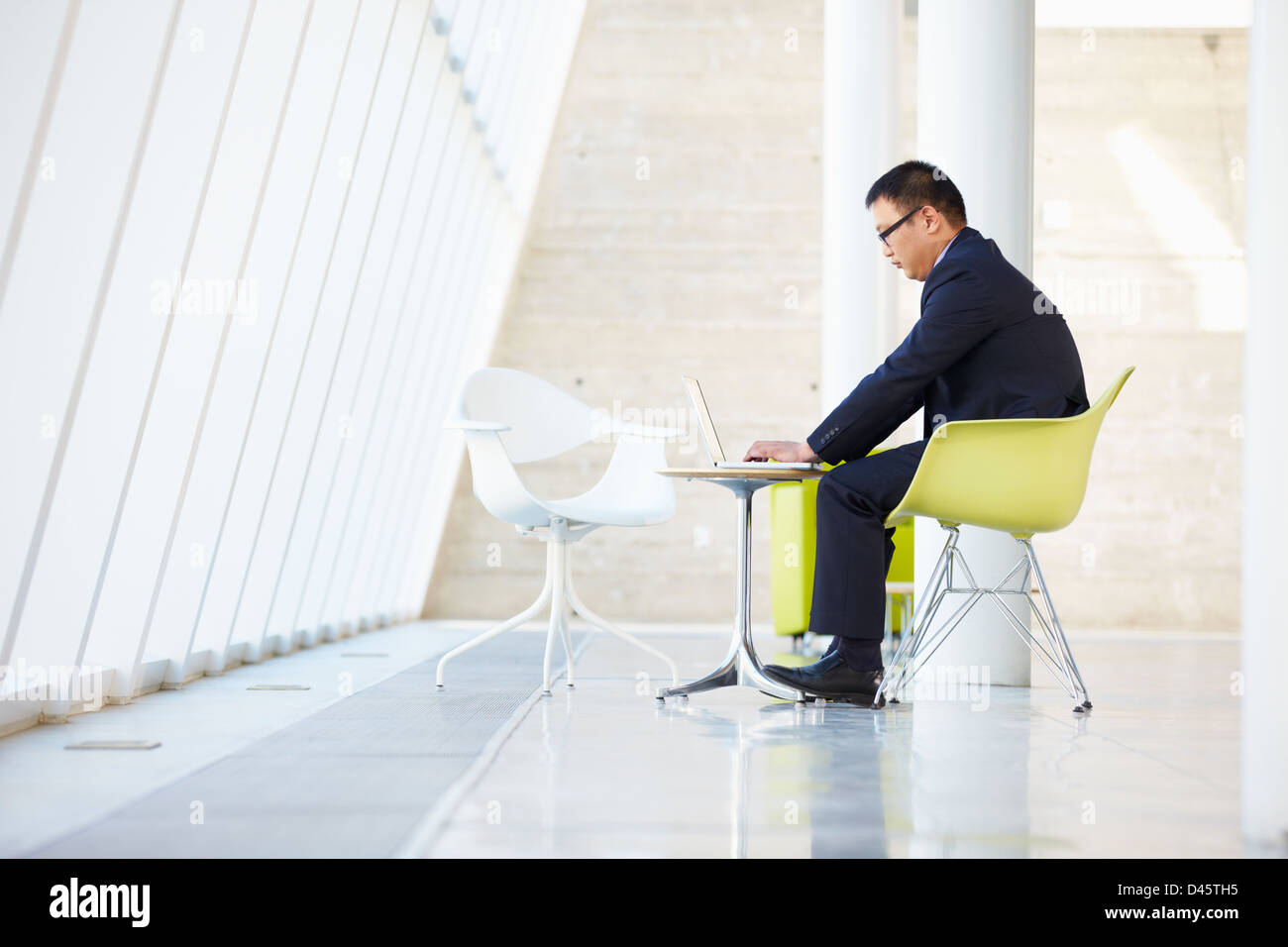 Businessman Working On Laptop At Table in Modern Office Banque D'Images