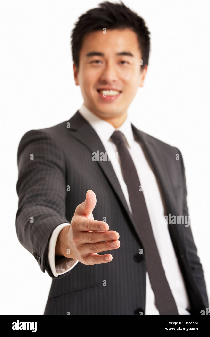 Studio Portrait of Chinese Businessman Reaching Out pour serrer la main Banque D'Images