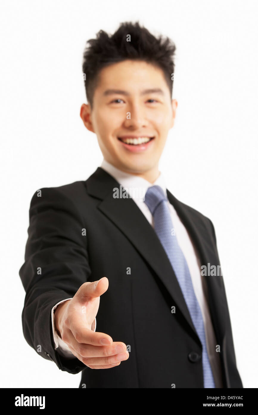 Studio Portrait of Chinese Businessman Reaching Out pour serrer la main Banque D'Images