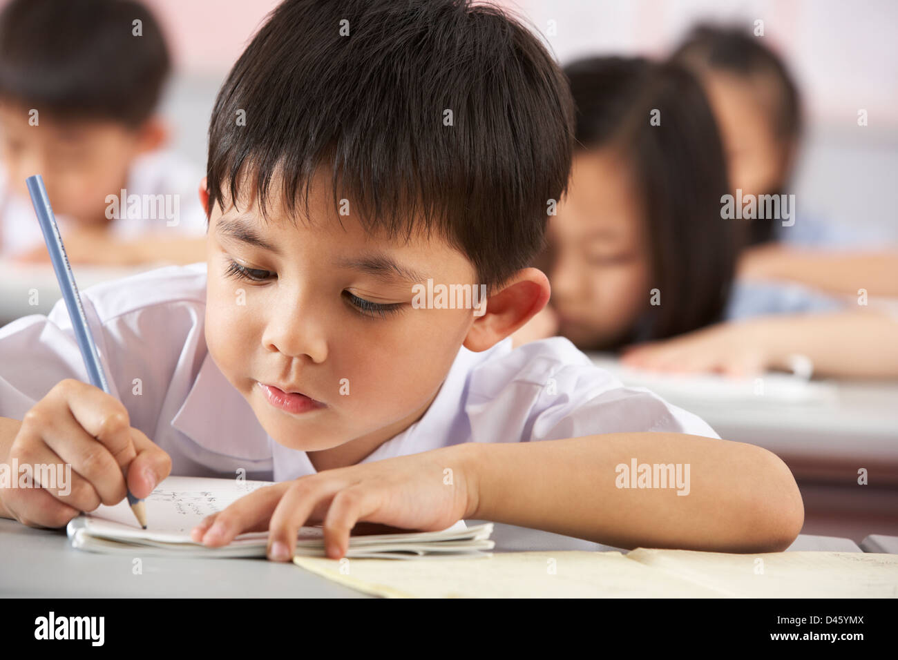 Groupe d'étudiants travaillant à un bureau en classe de l'école chinoise Banque D'Images