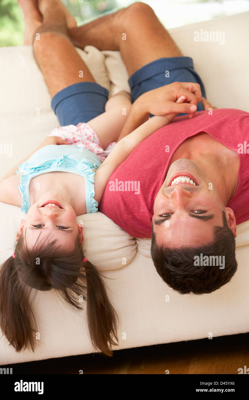Père couché à l'envers sur le canapé avec sa fille Banque D'Images