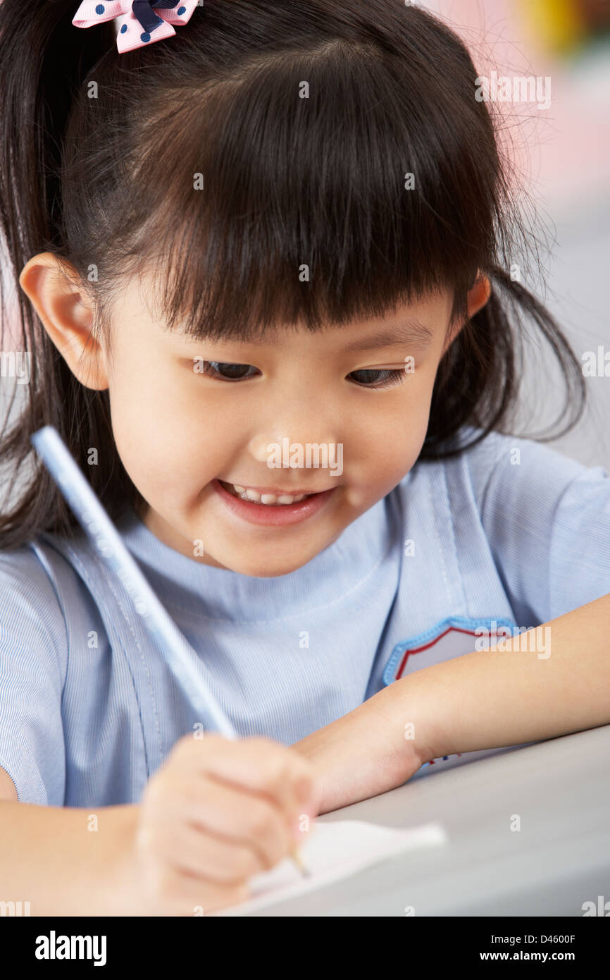 Female Student Working at Desk In Classroom école chinoise Banque D'Images