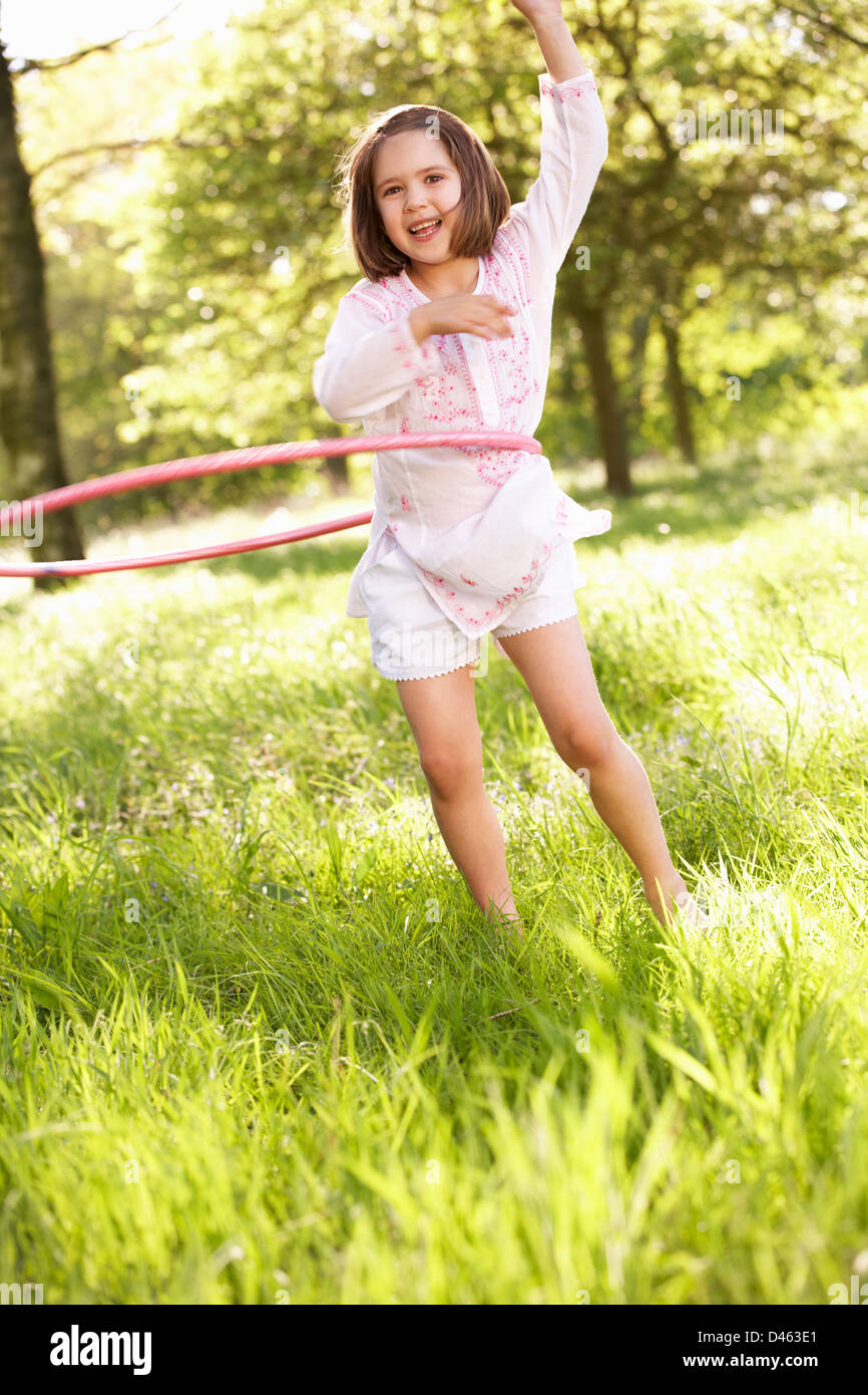 Jeune fille qui marche en jouant avec Hula Hoop Champ en été Banque D'Images