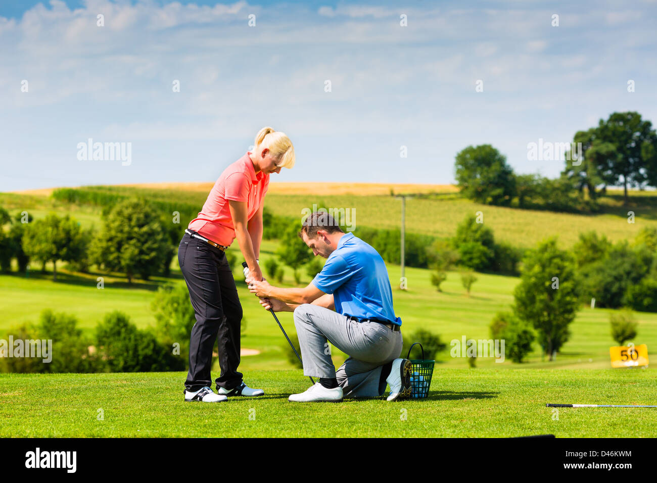 Jeune femme au joueur de golf driving range avec un Golf Pro, elle n'est sans doute l'exercice Banque D'Images