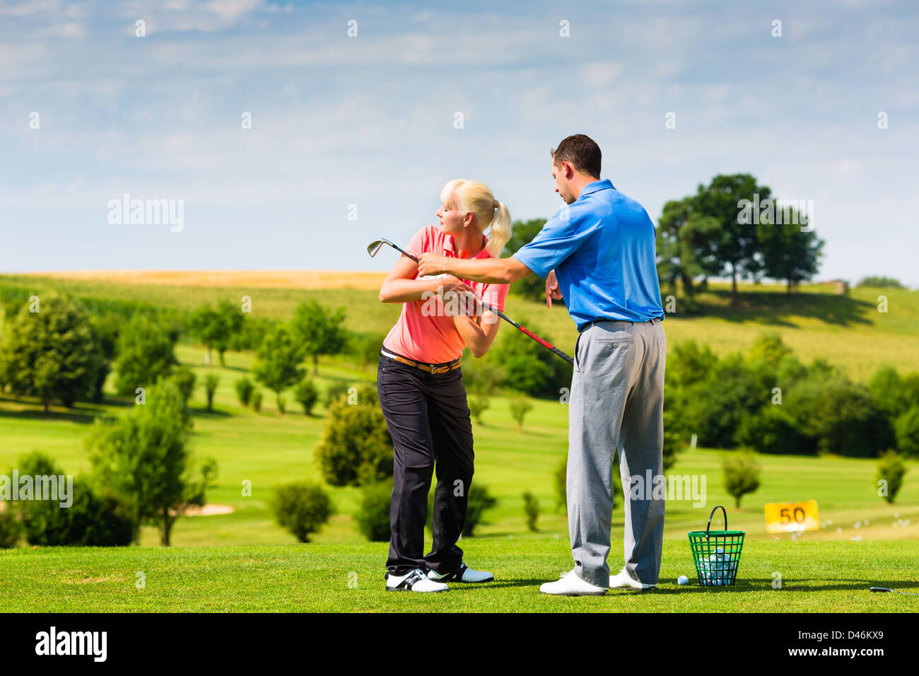 Jeune femme au joueur de golf driving range avec un Golf Pro, elle n'est sans doute l'exercice Banque D'Images