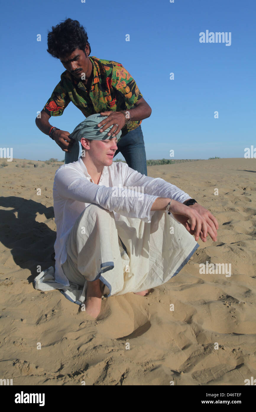 Un homme de l'Ouest a mis un turban sur sa tête par un Indien dans le désert de Thar. C'est au cours d'un chameau de Jaisalmer. Banque D'Images