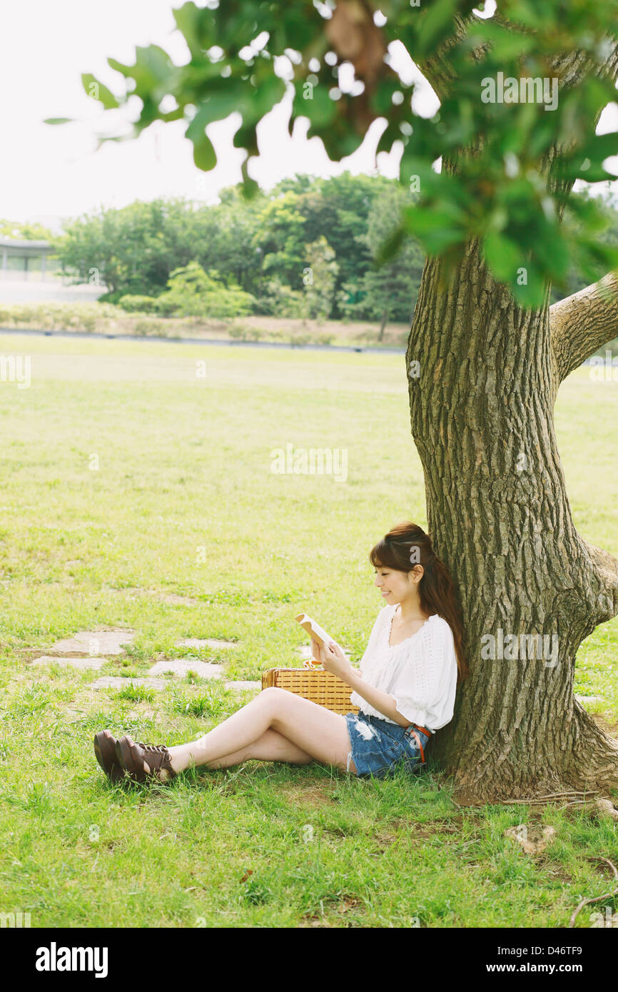 Femme lisant un livre dans le cadre de Tree Banque D'Images