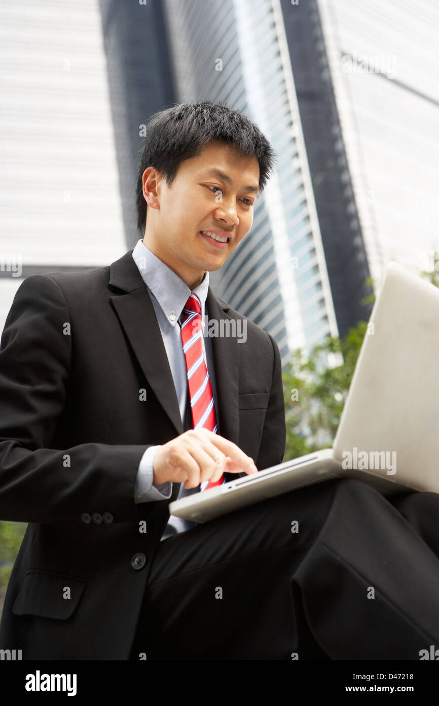 Chinese Businessman Working On Laptop Outside Office Banque D'Images