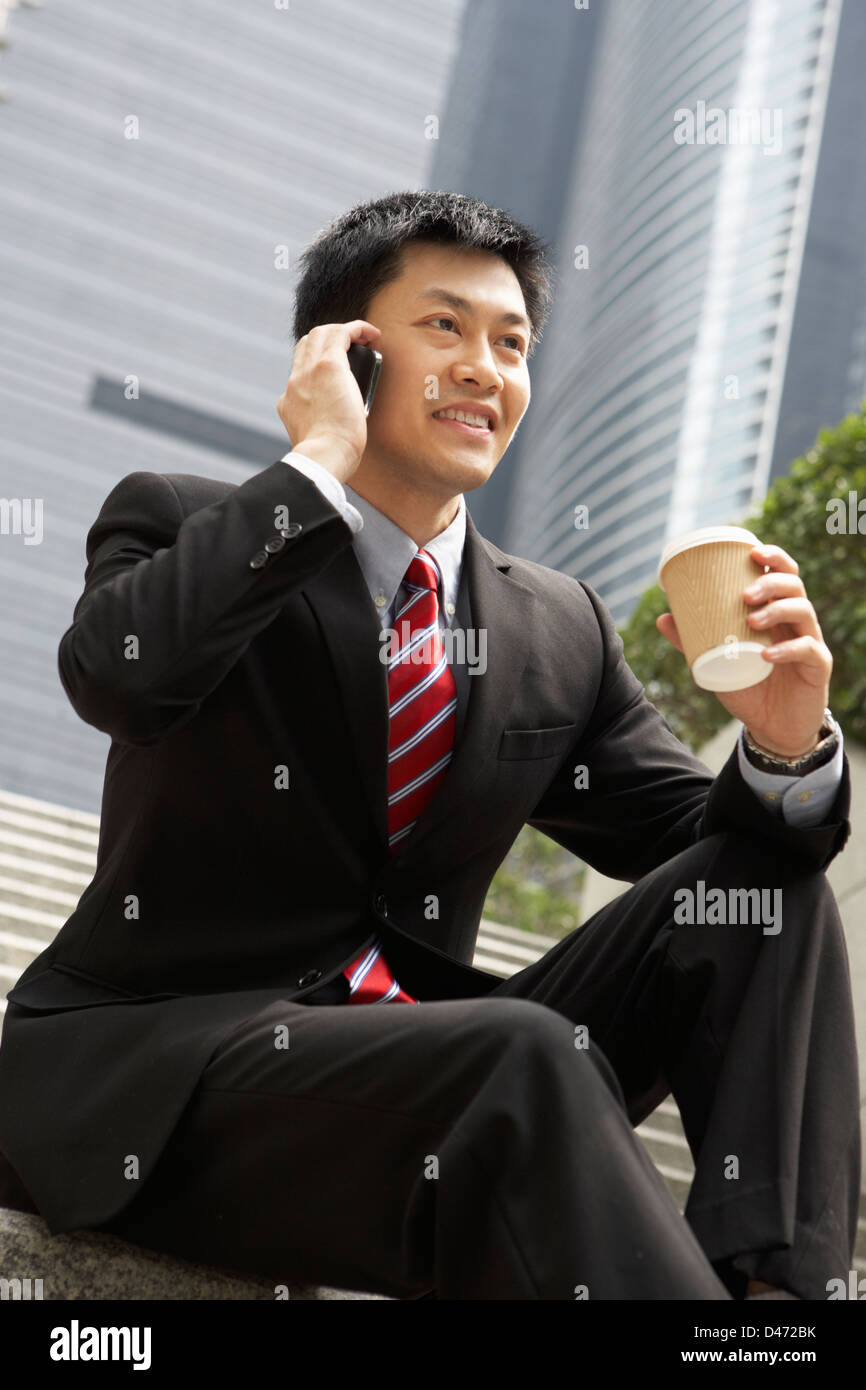 Chinese Businessman Talking On Mobile Phone avec café à emporter Banque D'Images