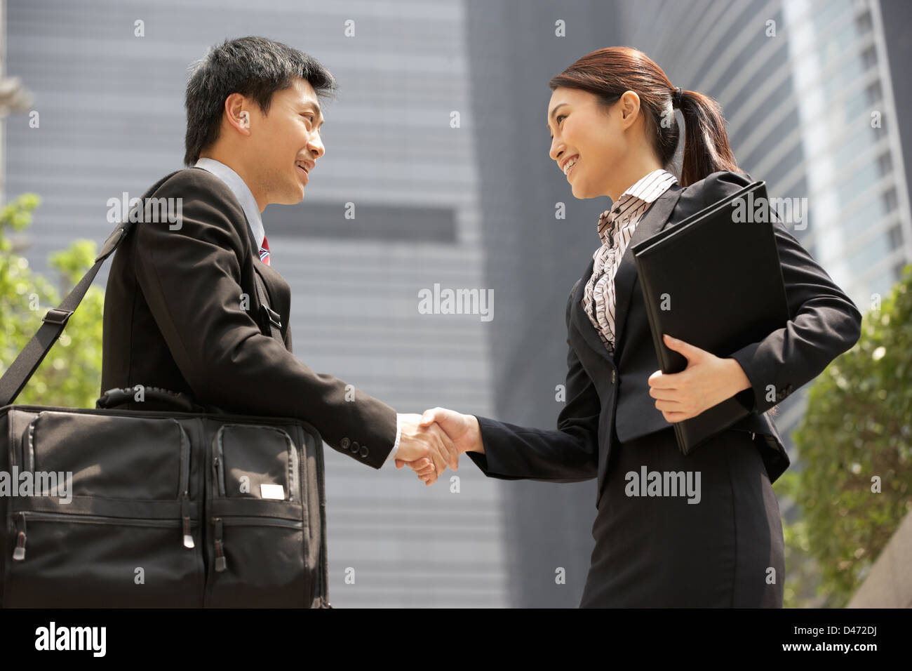 Chinese Businessman And Businesswoman Shaking Hands Outside Office Banque D'Images