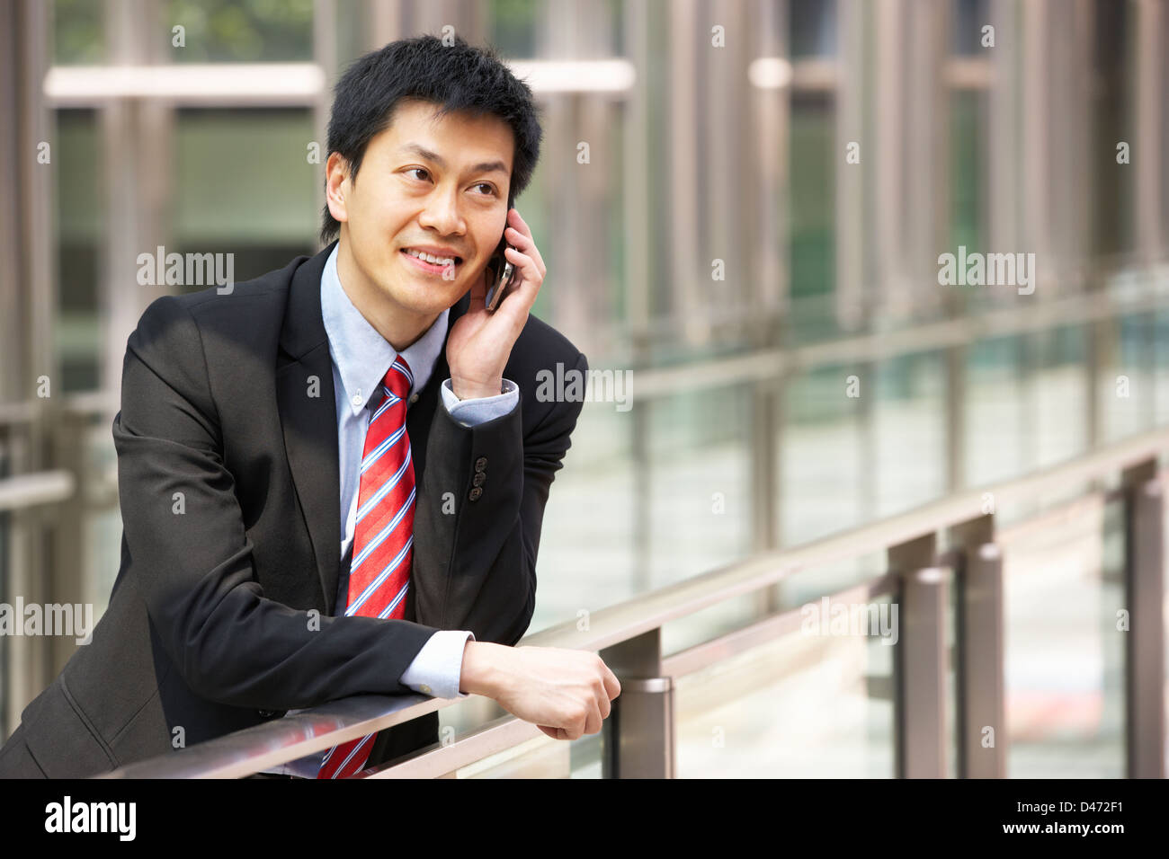 Portrait d'homme d'affaires chinois à l'extérieur du bureau sur téléphone mobile Banque D'Images