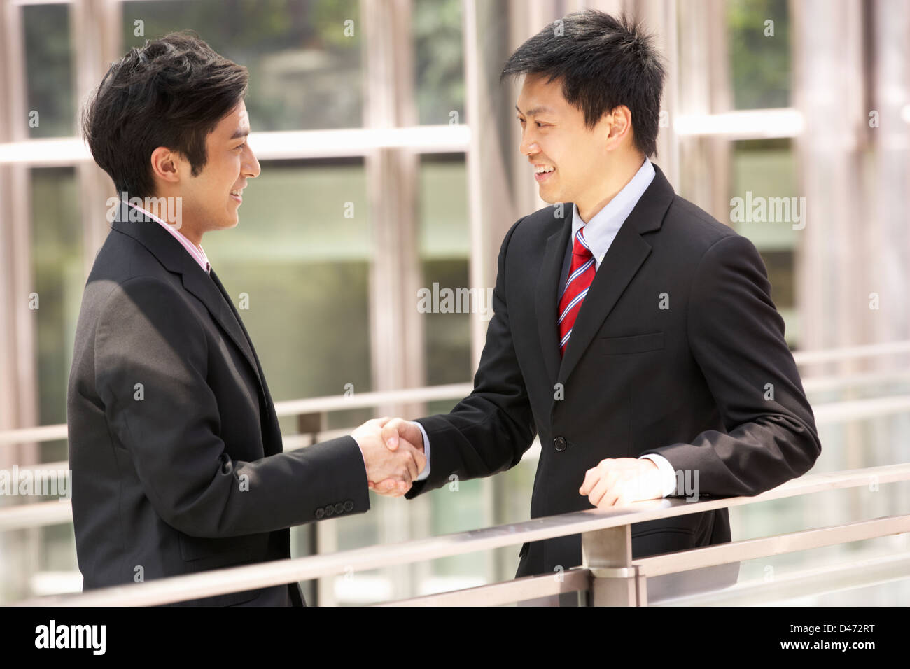 Deux hommes d'affaires chinois Shaking Hands Outside Office Banque D'Images