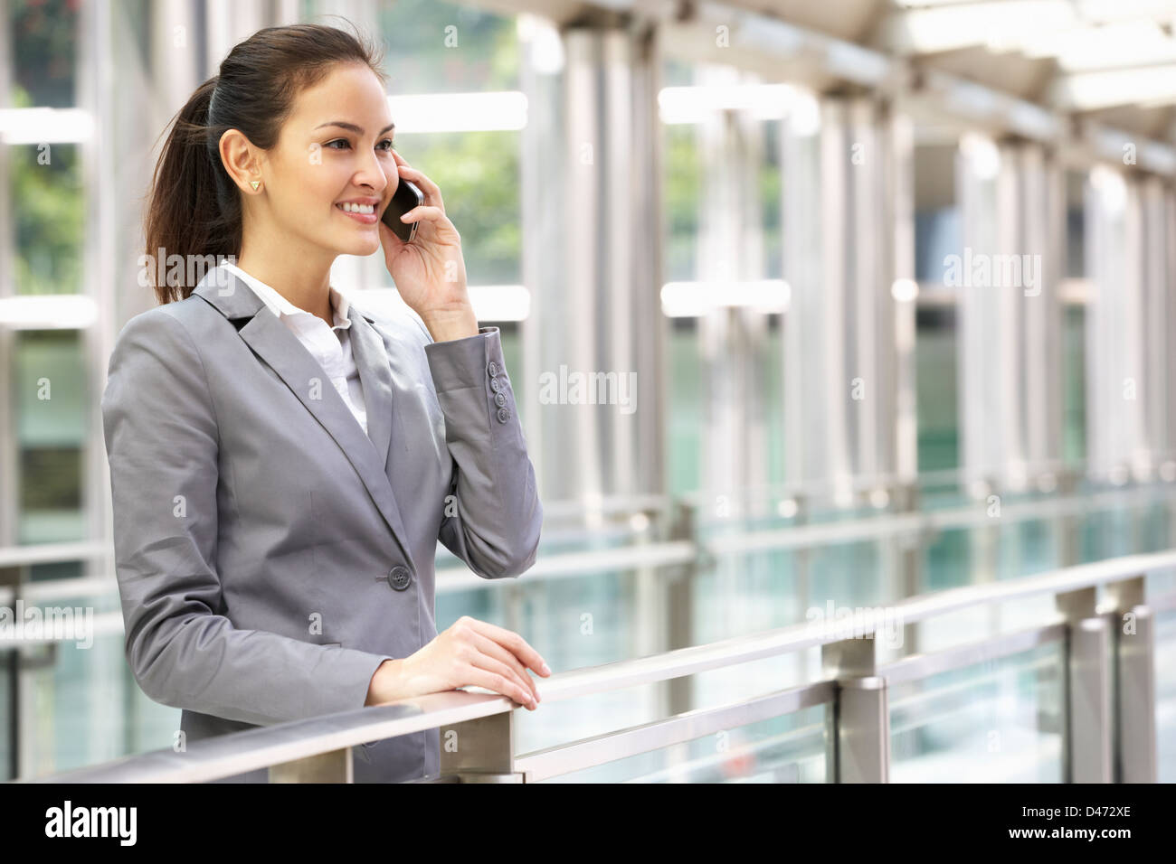 Hispanic Businesswoman Outside Office On Mobile Phone Banque D'Images