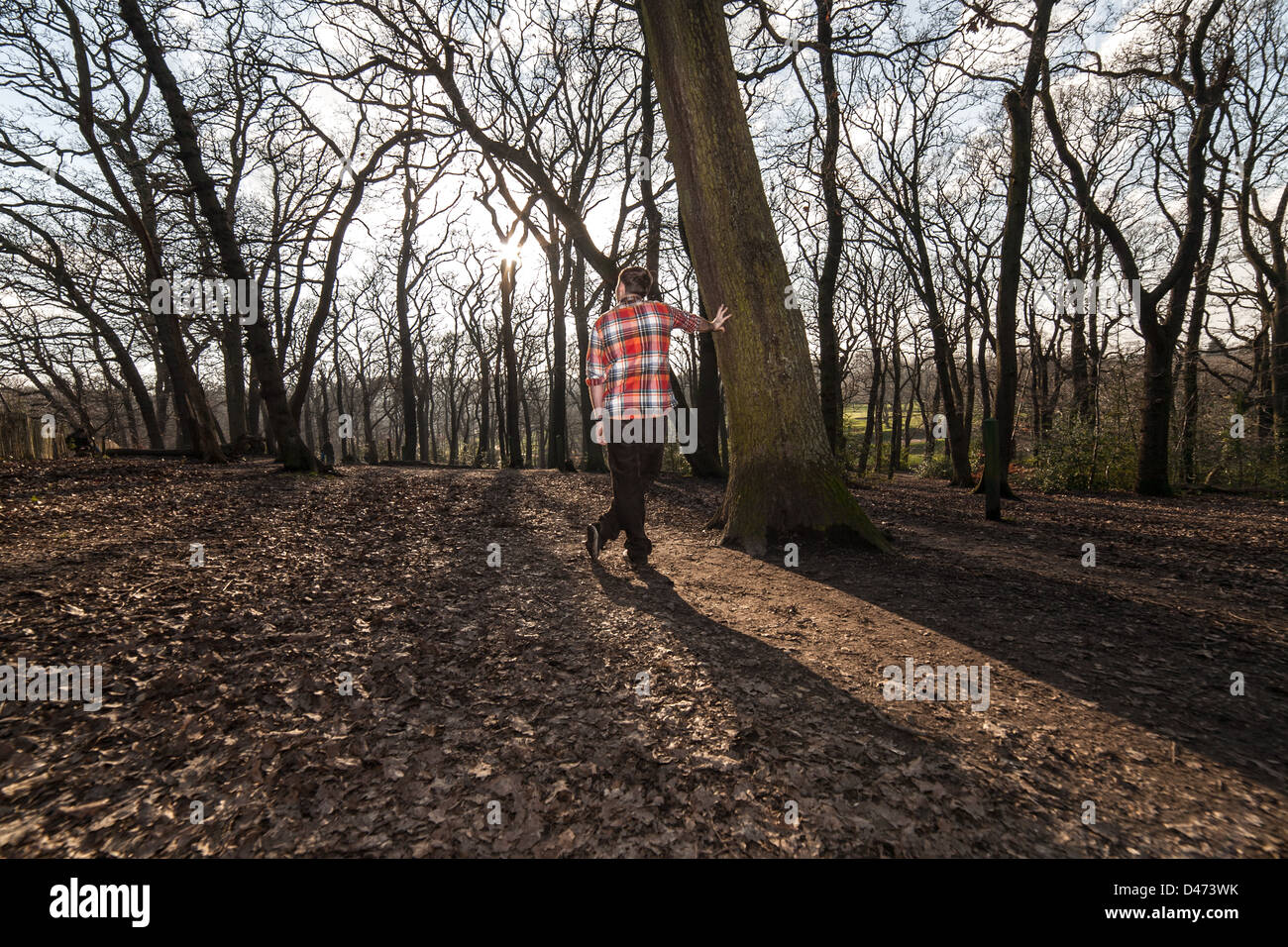 L'homme dans une chemise à carreaux rouge avec son nouveau à nous reposant contre un arbre, profitant d'une vue sur les bois Banque D'Images