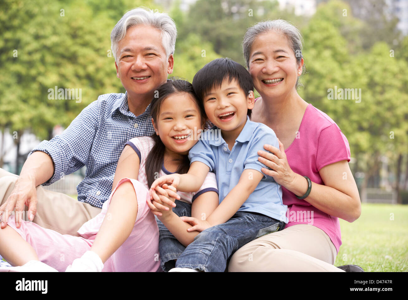 Les grands-parents chinois assis avec petits-enfants dans le parc Banque D'Images