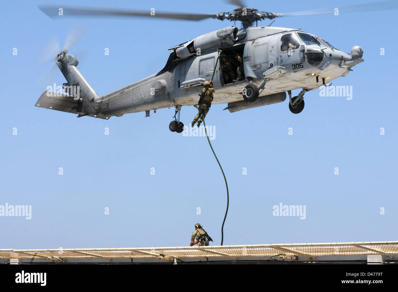 Une marine américaine SCELLE LES cordes rapides d'un hélicoptère HH-60H Sea Hawk lors d'exercices d'entraînement à long Beach, en Californie. L'opération fait partie de la formation spécialisée du SBT-12 pour la lutte contre le terrorisme maritime et les missions d'action directe. Banque D'Images