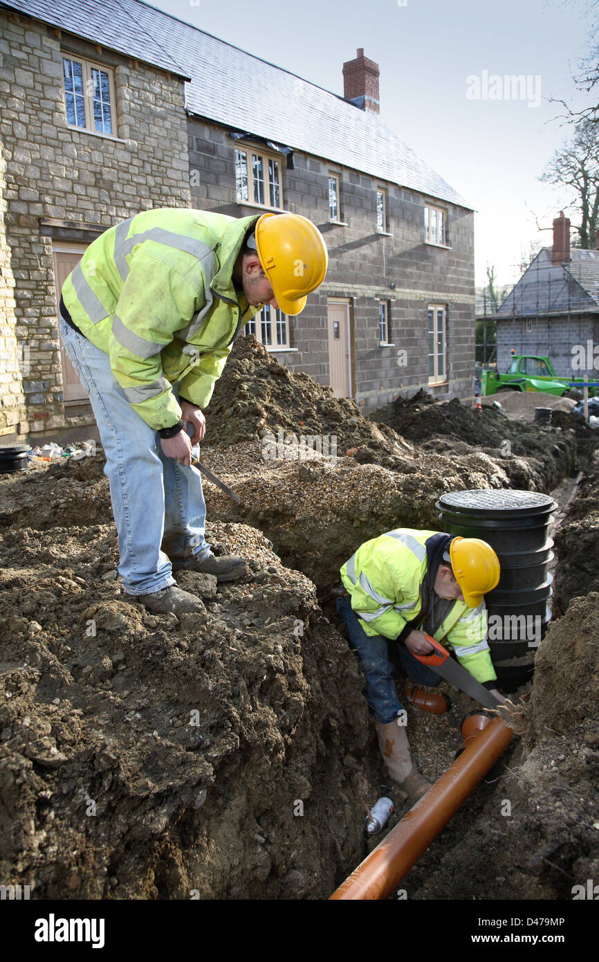 L'installation d'ouvriers tuyaux de drainage sur un développement du logement traditionnel dans le Dorset, UK Banque D'Images