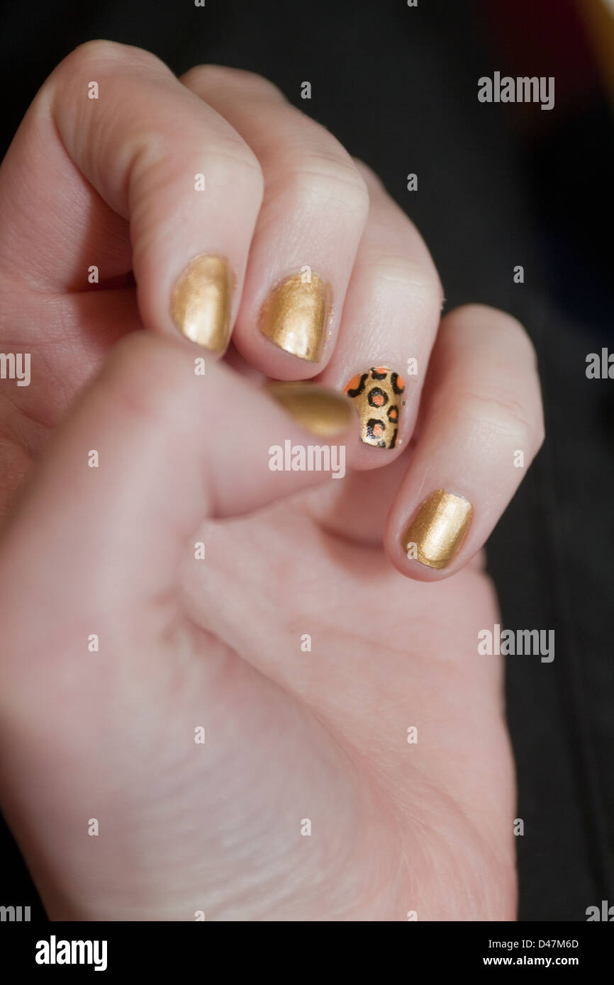 Main de la jeune fille avec de l'or peint les ongles et leopard print design Banque D'Images