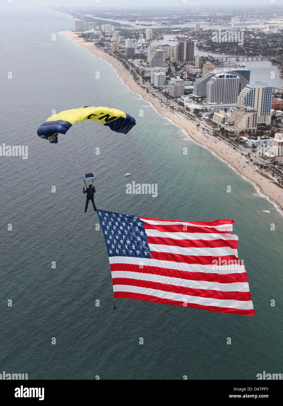 Un membre de l'équipe de démonstration de parachutistes des US Navy SEALs, les Leap Frogs, arborent un grand drapeau américain lors d'une répétition pour le Lauderdale Air Show à Fort Lauderdale, en Floride. Banque D'Images Un membre de l'équipe de démonstration de parachutistes des US Navy SEALs, les Leap Frogs, arborent un grand drapeau américain lors d'une répétition pour le Lauderdale Air Show à Fort Lauderdale, en Floride. Banque D'Images