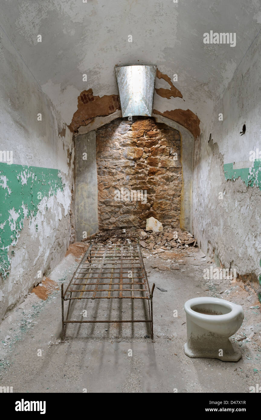 Cellule de prison abandonnée avec cadre de lit et de toilettes, au Pénitentiaire de l'état de ruines, Philaelphia, PA, USA. Banque D'Images
