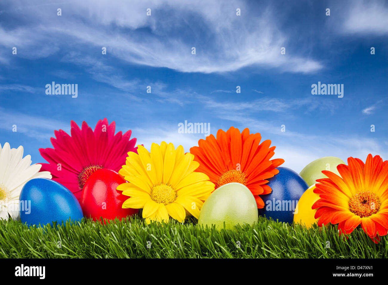 Les oeufs de Pâques colorés avec des fleurs sur l'herbe Banque D'Images