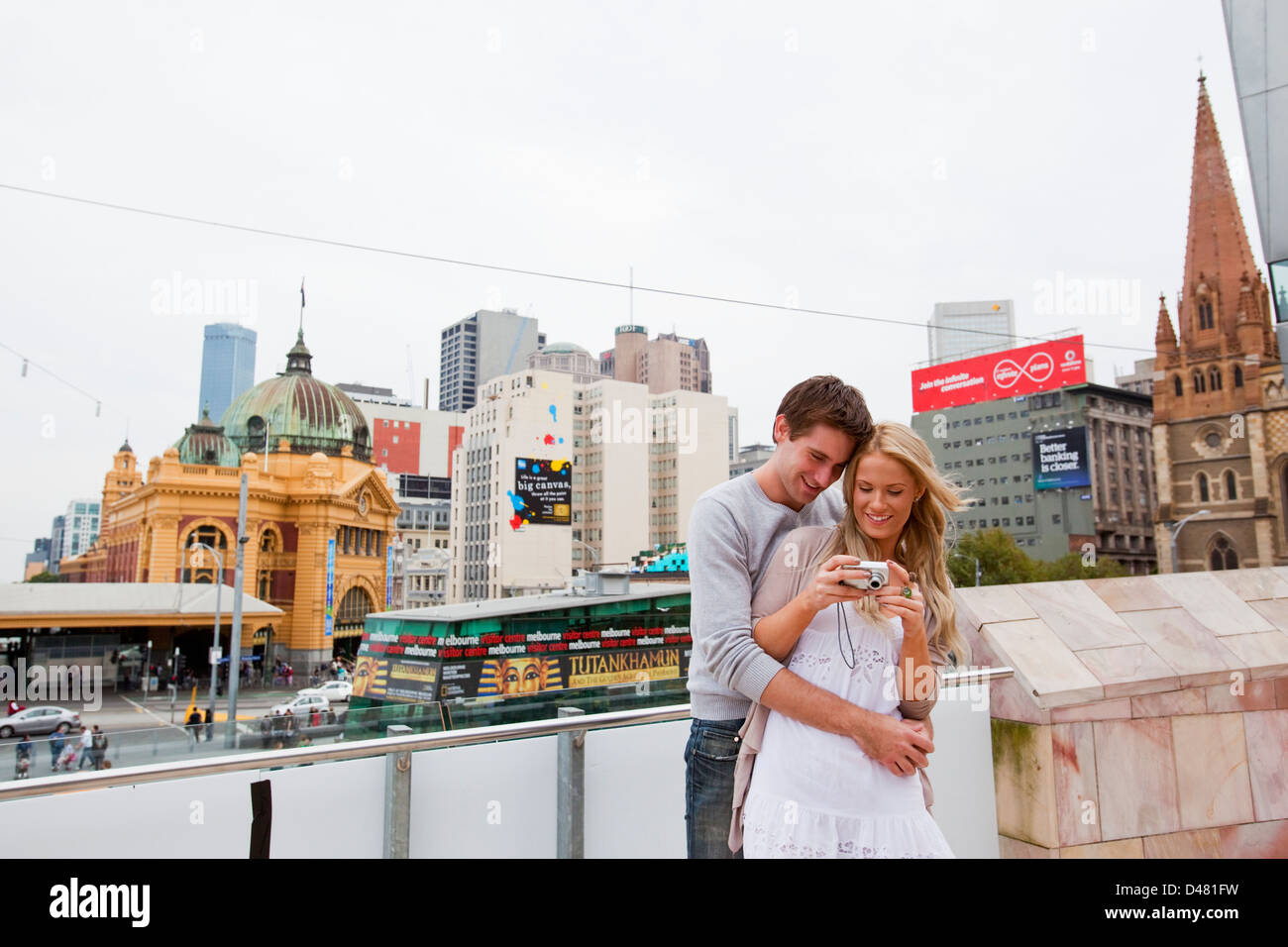 Jeune couple de visites dans la ville, regarder des images sur l'appareil-photo. Federation Square, Melbourne, Victoria, Australie Banque D'Images