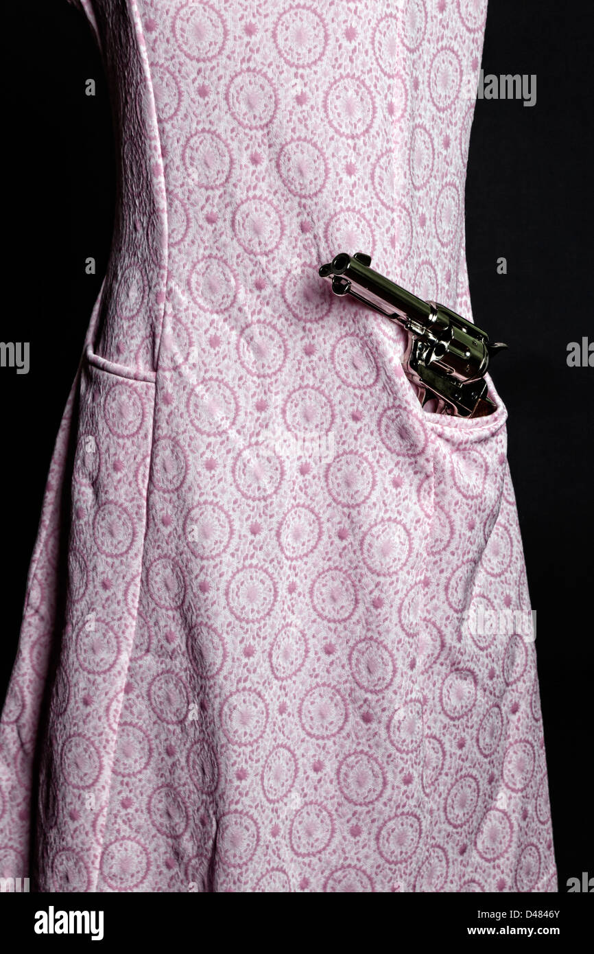 Une arme à feu dans une poche d'une robe rose Banque D'Images