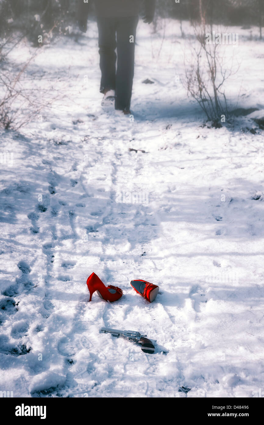 Red High Heels et un fusil dans la neige, un homme est en marche Banque D'Images
