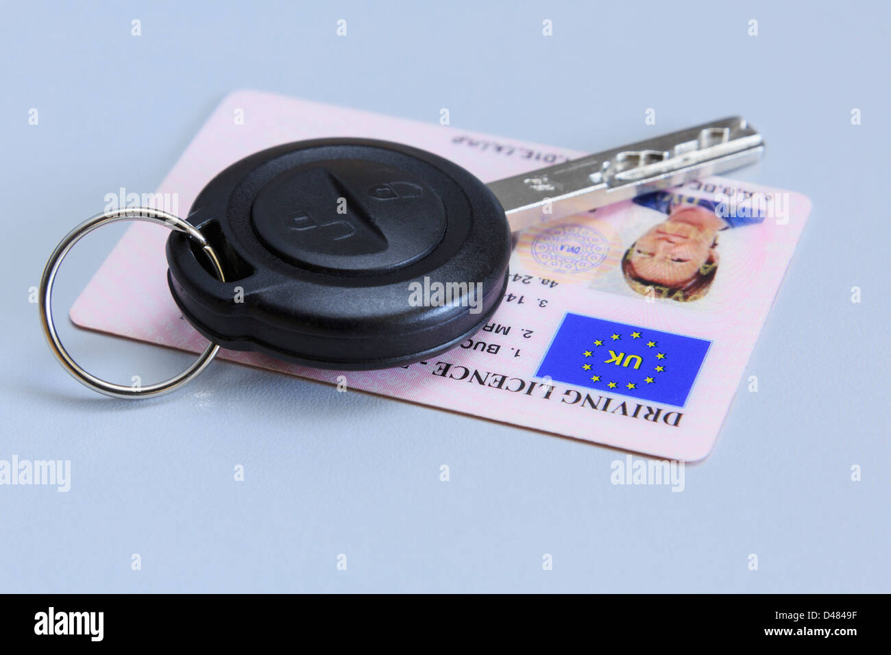 Clé de voiture à distance avec une carte en plastique de femme UK driving license photographique sur un fond bleu. Banque D'Images