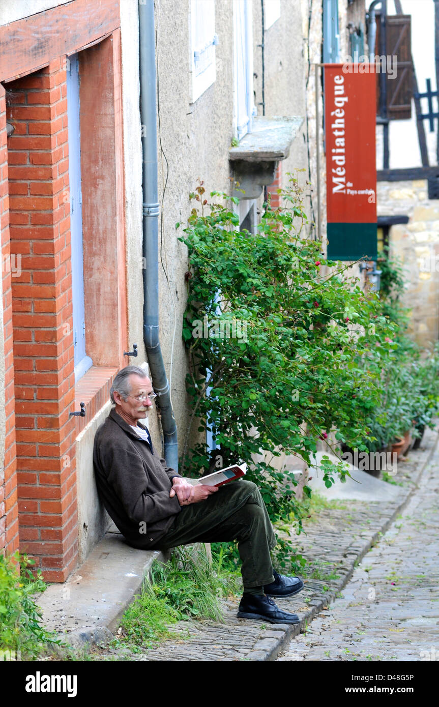 Homme lisant un livre à l'extérieur de la bibliothèque multimédia plus moderne. Cordes, Tarn, France Banque D'Images