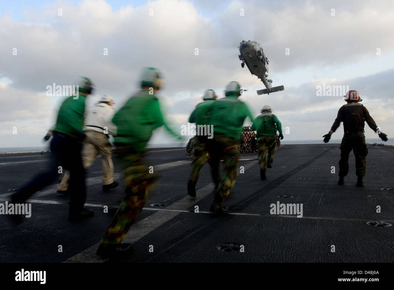 Les marins à bord d'un navire de l'US Navy récupèrent la cargaison larguée d'un hélicoptère MH-60S Seahawk lors d'une opération dans la zone de responsabilité de la 5e flotte américaine. Banque D'Images