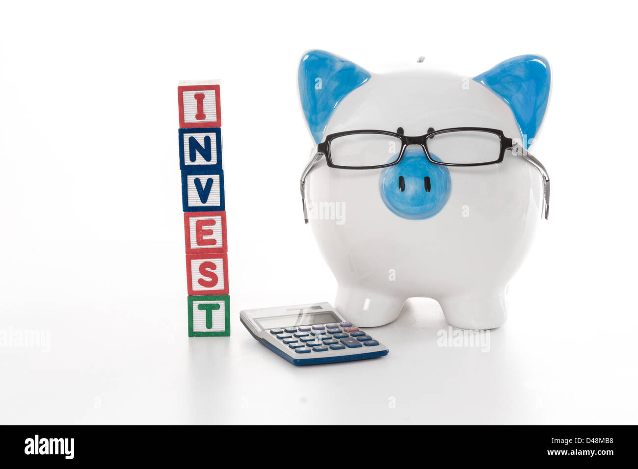 Blue and White piggy bank wearing glasses avec blocs de construction investir Banque D'Images