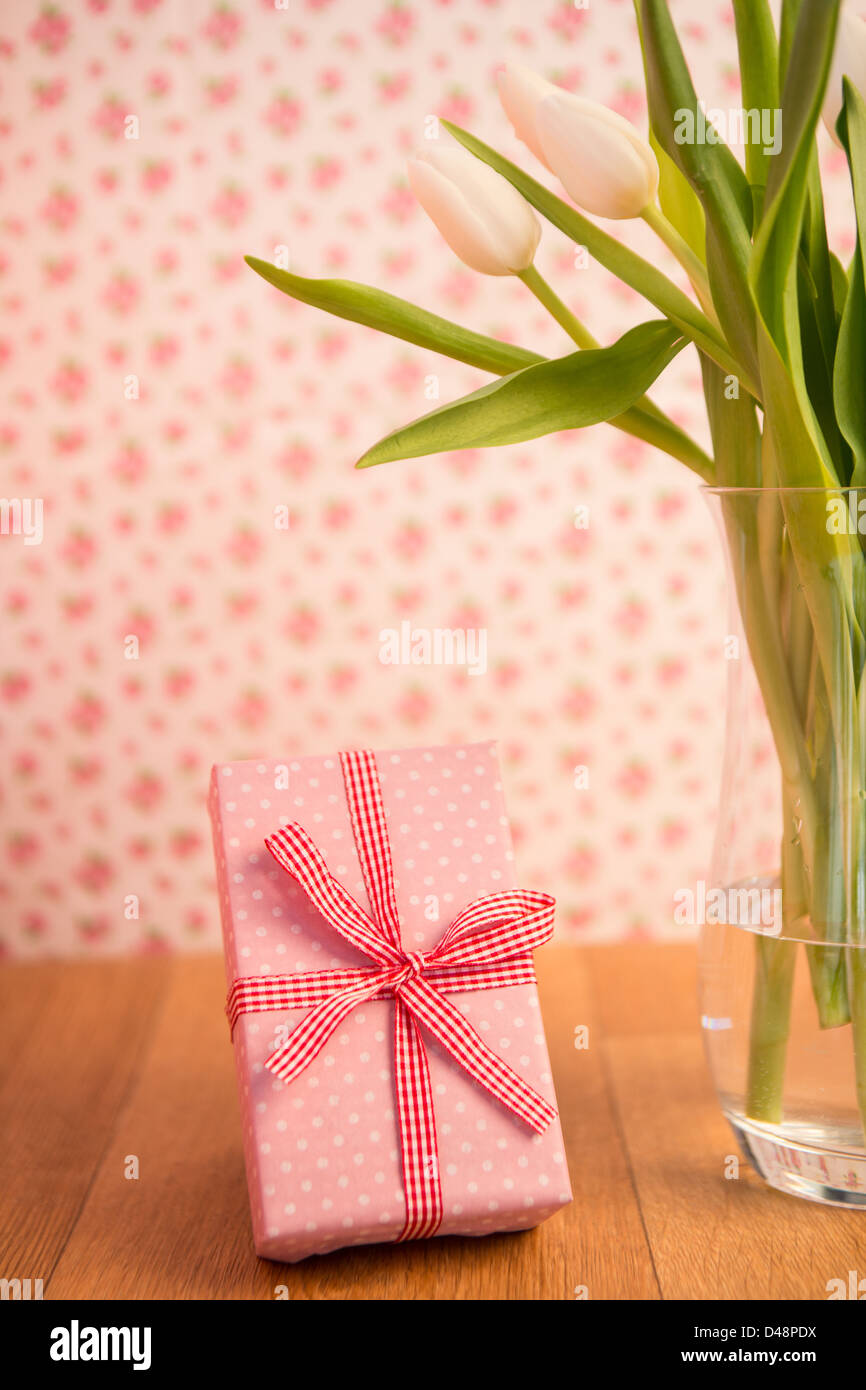 Vase de tulipes sur table en bois avec rose cadeau enveloppé Banque D'Images