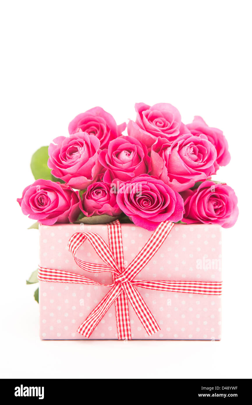 Bouquet de belles roses à côté d'un cadeau rose sur fond blanc Banque D'Images