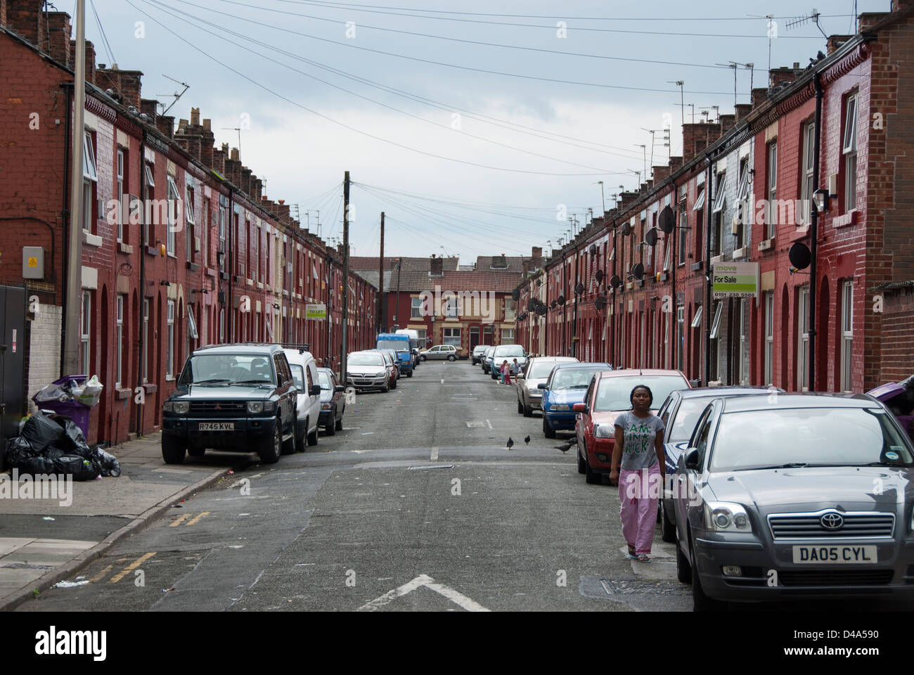 Dans le quartier pauvre de la rue avec des maisons à vendre, de saleté, de détritus et une femme immigrante à marcher vers l'appareil photo Banque D'Images