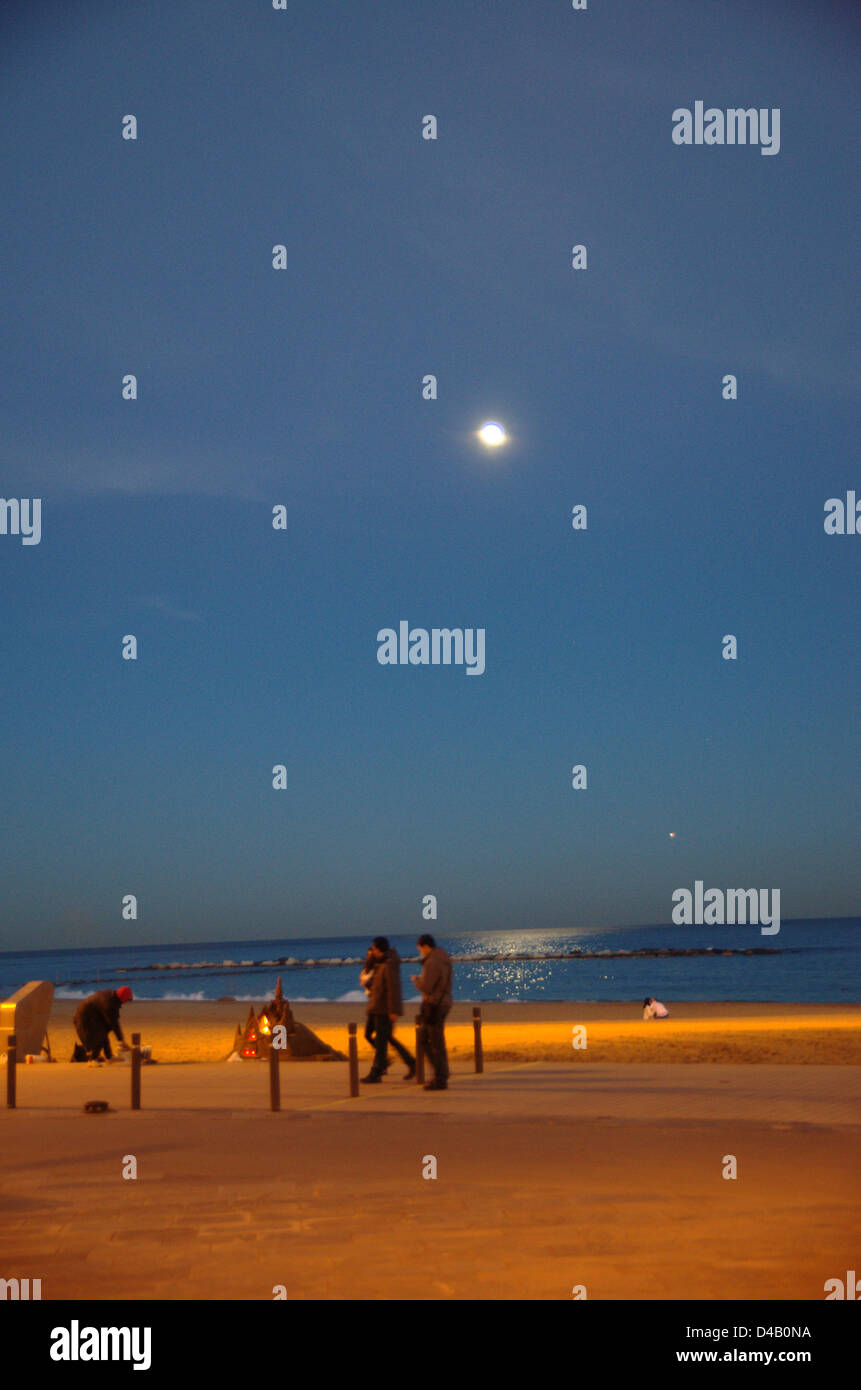 Température sur la plage de Barcelone la nuit. Une personne fait des châteaux de sable. Banque D'Images