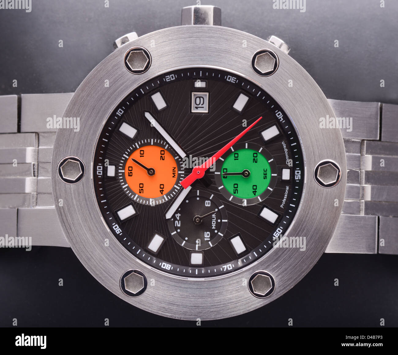 Un gros plan d'une montre sport en acier épais avec noir, orange et vert compose Banque D'Images