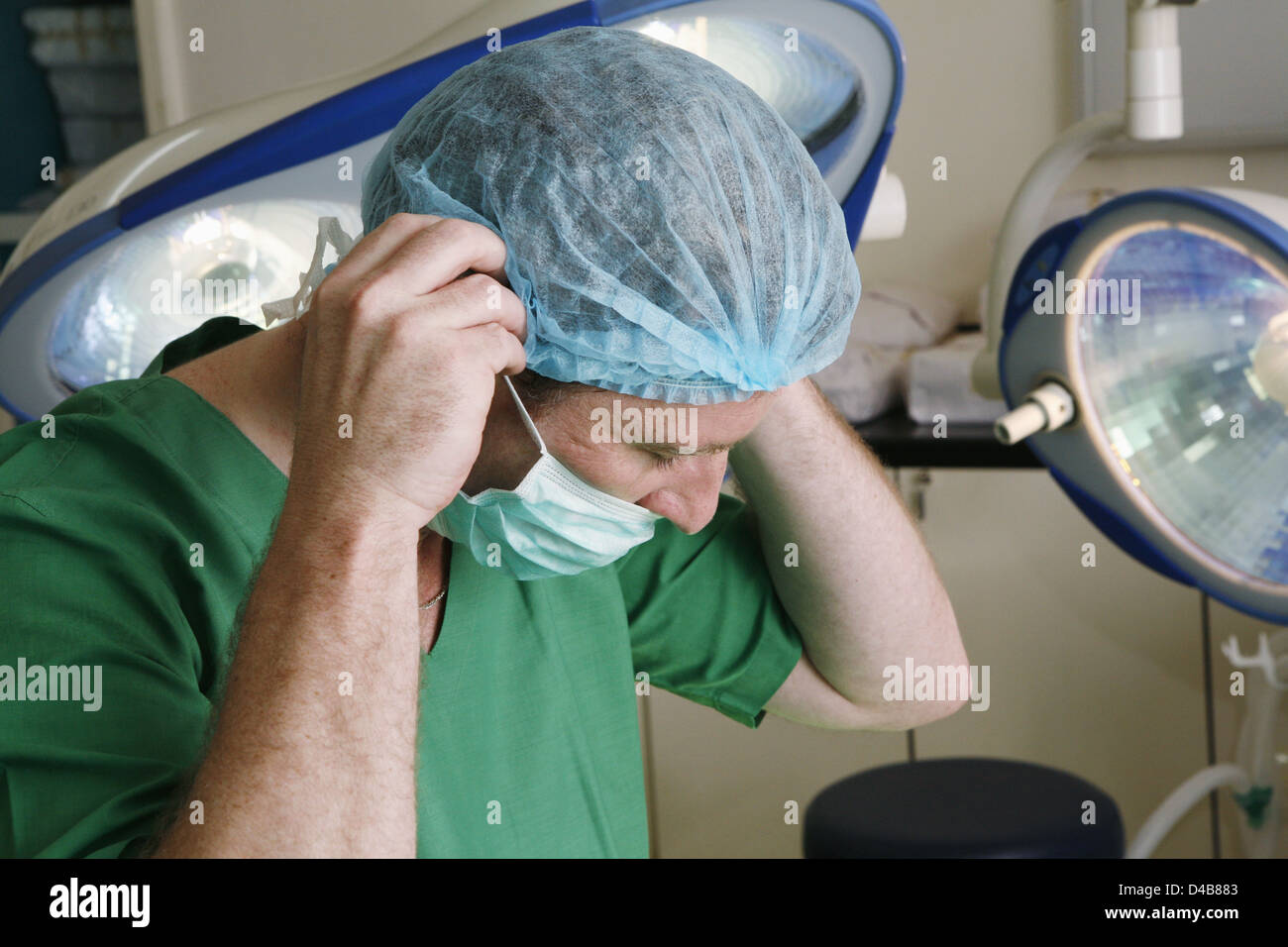 Chirurgien de l'hôpital régler son masque chirurgical sous les lumières dans le théâtre d'exploitation Banque D'Images