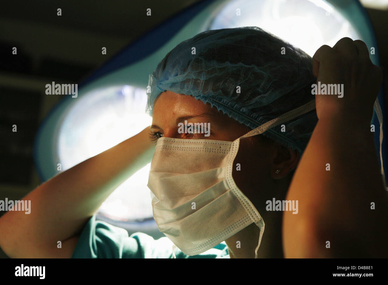 Chirurgienne ses liens masque chirurgical autour de son visage sous témoins de fonctionnement Banque D'Images