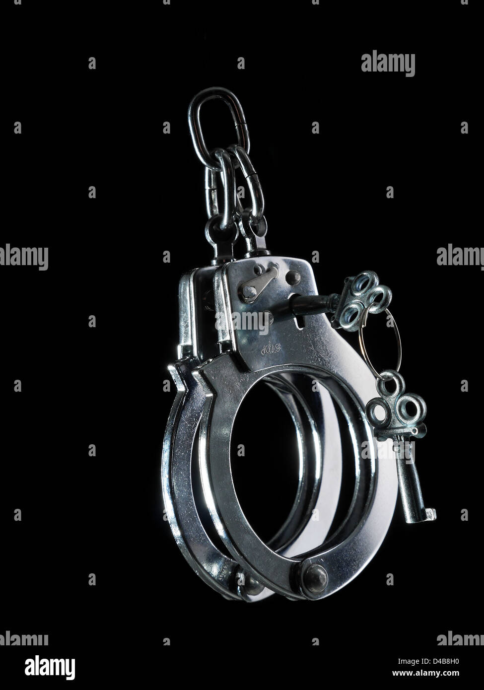 La police menottes en acier avec clés de déverrouillage tourné sur fond noir Banque D'Images