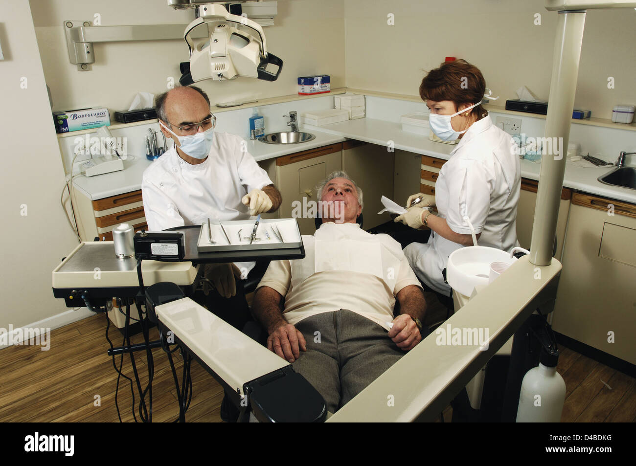 Dans l'attente du traitement de patients dentaires masculins, s'étendant entre dentiste et assistante Banque D'Images