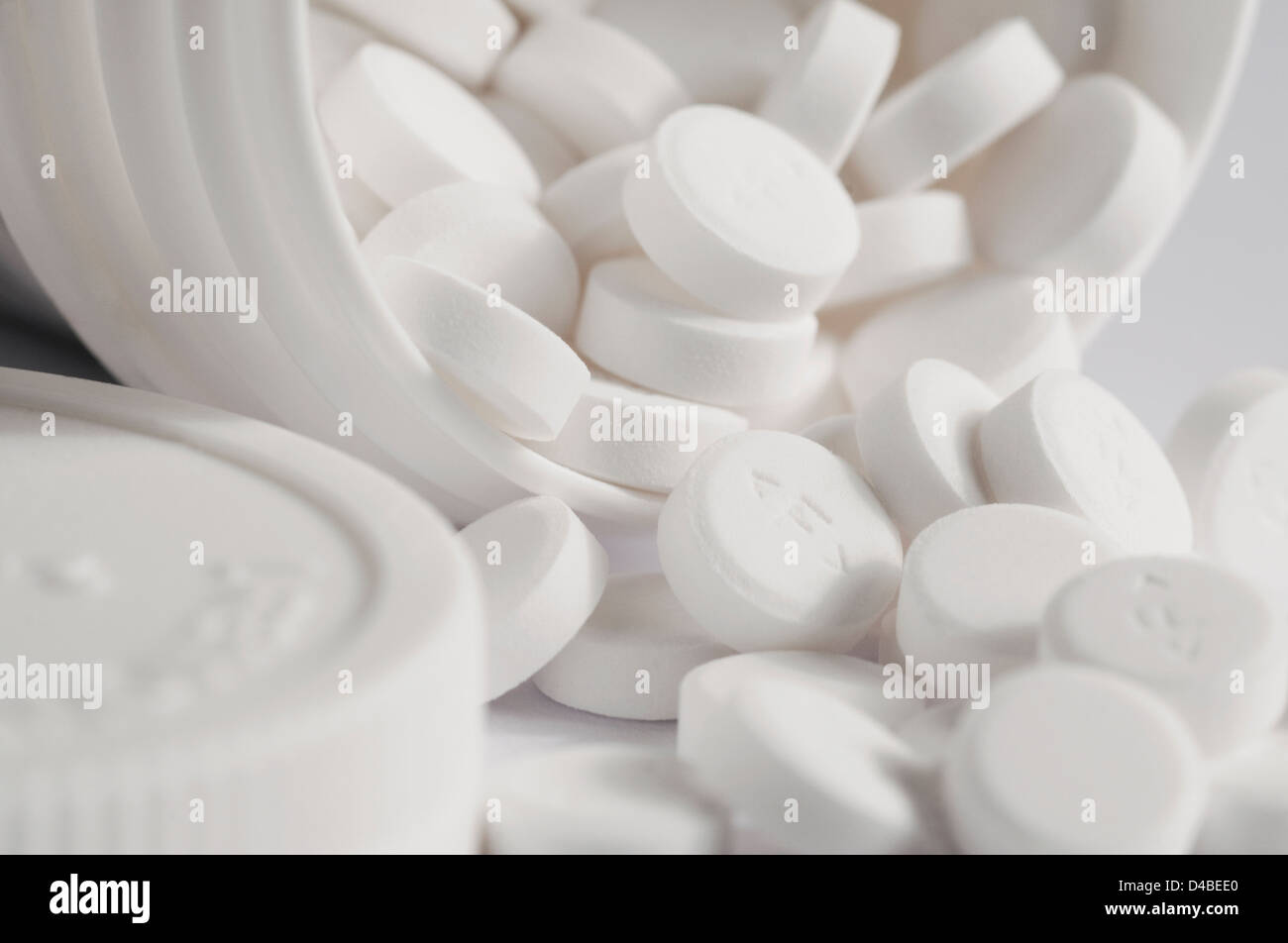 les comprimés d'aspirine débordent du contenant blanc Banque D'Images