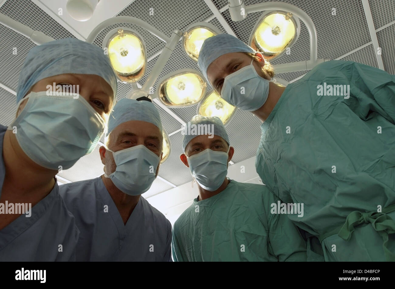 Les patients considèrent de l'équipe de chirurgiens masqués sous des lampes à l'hôpital d'opération Banque D'Images